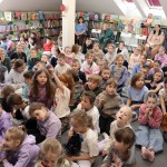 Powiększ zdjęcie Dzieci siedzą na podłodze w bibliotece