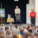 Powiększ zdjęcie Dzieci siedzą na podłodze w bibliotece i dwie osoby dorosłe