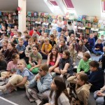 Powiększ zdjęcie Dzieci siedzą na podłodze w bibliotece 