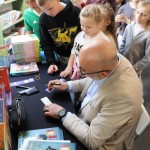 Powiększ zdjęcie Autor podpisuje książki dzieciom