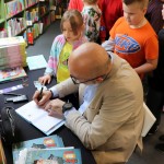 Powiększ zdjęcie Autor podpisuje książki dzieciom