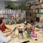 Powiększ zdjęcie Uczestniczki klubu miłośników książek w bibliotece siedzą przy stole