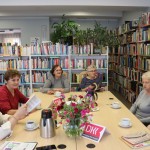 Powiększ zdjęcie Uczestniczki klubu miłośników książek w bibliotece siedzą przy stole