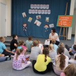 Powiększ zdjęcie Dzieci siedzą na podłodze w bibliotece i rozmawiają z panią