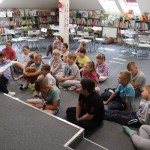 Powiększ zdjęcie Dzieci siedzą na podłodze w bibliotece