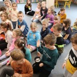 Powiększ zdjęcie Dzieci siedzą na podłodze w bibliotece