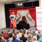 Powiększ zdjęcie Dzieci siedzą na podłodze w bibliotece i oglądają przedstawienie