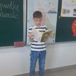 Powiększ zdjęcie Na zdjęciu uczeń przy tablicy czytający książkę