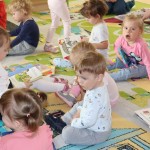 Powiększ zdjęcie Dzieci oglądają na dywanie książeczki