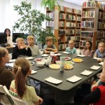 Powiększ zdjęcie Dzieci siedzą przy stole na którym stoją smakołyki