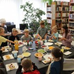 Powiększ zdjęcie Dzieci siedzą przy stole i zajadają gofry