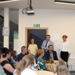 Powiększ zdjęcie Przy stolikach siedzą zaproszeni goście, mężczyzna przemawia