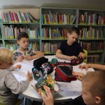 Powiększ zdjęcie Na zdjęciu dzieci w bibliotece wykonują pracę plastyczną