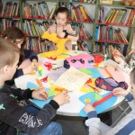 Powiększ zdjęcie Dzieci przy stoliku wycinają kwiatki z kolorowego papieru