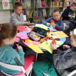 Powiększ zdjęcie Dzieci przy stoliku wycinają kwiatki z kolorowego papieru