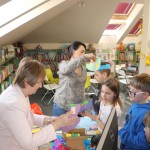 Powiększ zdjęcie Bibliotekarki pomagają zakładać kapelusze dzieciom
