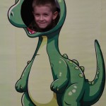 Powiększ zdjęcie Chłopiec w fotobudce zielonego dinozaura