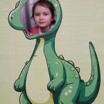 Powiększ zdjęcie Dziewczynka w fotobudce zielonego dinozaura