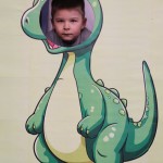 Powiększ zdjęcie Chłopiec w fotobudce zielonego dinozaura