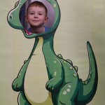 Powiększ zdjęcie Chłopiec w fotobudce zielonego dinozaura