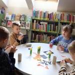 Powiększ zdjęcie Dzieci siedzą przy stolikach i wykonują prace plastyczną