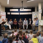 Powiększ zdjęcie Dzieci siedzą na podłodze w bibliotece pani dyrektor wita gości