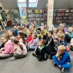 Powiększ zdjęcie Dzieci siedzą na podłodze w bibliotece