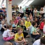 Powiększ zdjęcie Dzieci siedzą na podłodze w bibliotece