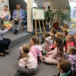 Powiększ zdjęcie Pani dyrektor przedszkola pokazuje książkę dzieciom siedzącym na podłodze